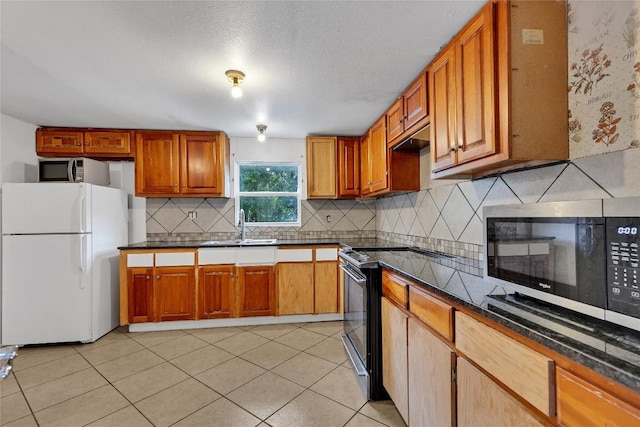 101 E Ash St, Granger, TX 76530 - kitchen with freestanding refrigerator, black electric range oven, stainless steel microwave, and tasteful backsplash