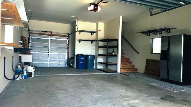2502 Grey Kirby Dr, League City, TX 77573 - garage featuring black fridge with ice dispenser and a garage door opener