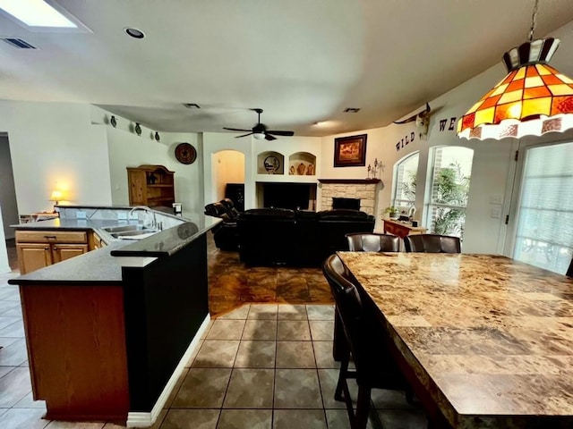 106 Hobbs Creek Cv, Cedar Creek, TX 78612 - kitchen featuring a large island with sink, dark tile patterned flooring, ceiling fan, built in features, and lofted ceiling