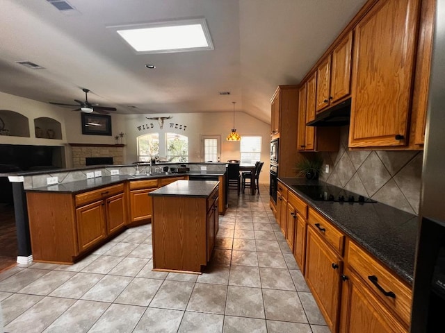 106 Hobbs Creek Cv, Cedar Creek, TX 78612 - kitchen with a kitchen island, black electric stovetop, brown cabinetry, decorative backsplash, and lofted ceiling