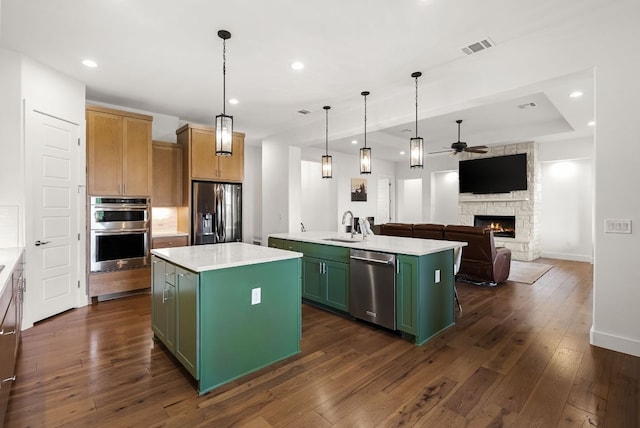 104 Huerta Rd, Florence, TX 76527 - kitchen featuring stainless steel appliances, green cabinetry, a kitchen island with sink, ceiling fan, and a fireplace