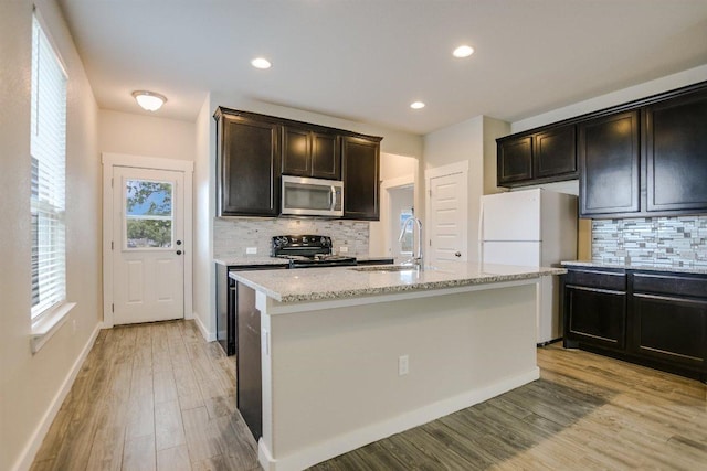 124 Ancellotta Way, Leander, TX 78641 - kitchen with stainless steel microwave, electric range, tasteful backsplash, freestanding refrigerator, and light stone counters