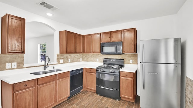 13124 Winecup Mallow Trl, Elgin, TX 78621 - kitchen with black appliances, wood finished floors, arched walkways, light countertops, and backsplash