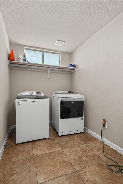 204 Archipelago Trl, Austin, TX 78717 - laundry room featuring washing machine and dryer, a textured ceiling, and tile patterned flooring