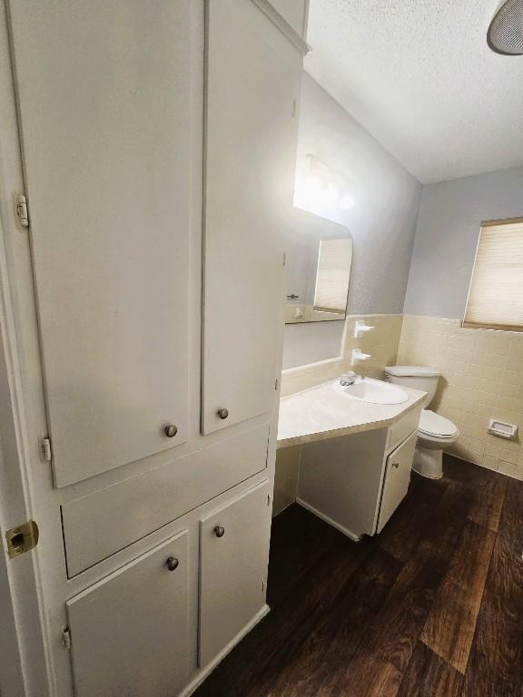 917 Edwards St S, Copperas Cove, TX 76522 - bathroom with vanity, wood finished floors, tile walls, a wainscoted wall, and a textured ceiling