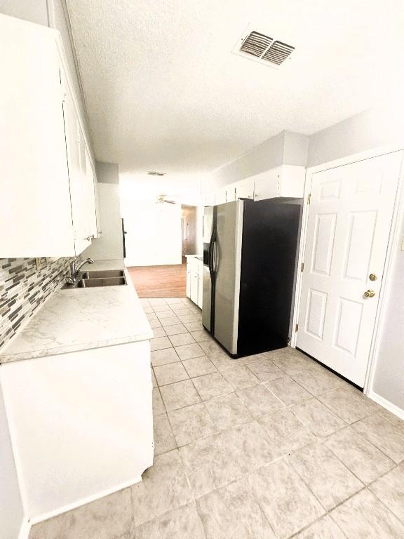 917 Edwards St S, Copperas Cove, TX 76522 - kitchen with stainless steel refrigerator with ice dispenser, light countertops, white cabinetry, backsplash, and light tile patterned floors