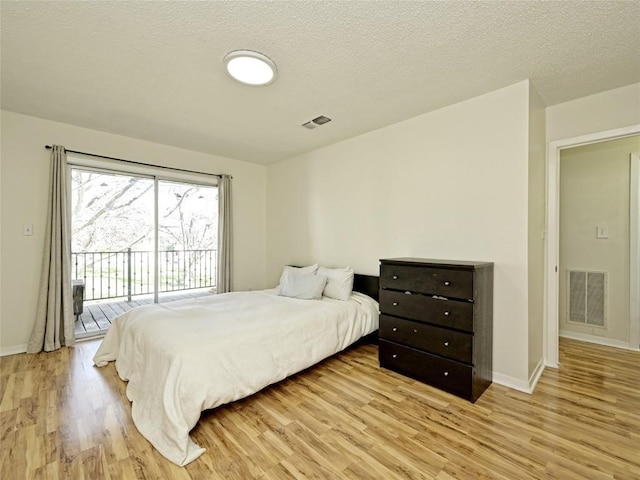 100 Lido Cir Unit A1, Lakeway, TX 78734 - bedroom with access to exterior, light wood-type flooring, and a textured ceiling
