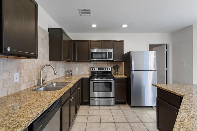 509 Red Tailed Hawk Dr, Pflugerville, TX 78660 - kitchen with appliances with stainless steel finishes, dark brown cabinetry, backsplash, light stone countertops, and light tile patterned flooring