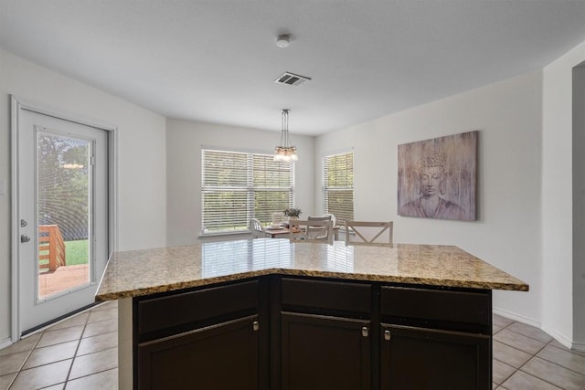 509 Red Tailed Hawk Dr, Pflugerville, TX 78660 - kitchen featuring light tile patterned floors, a chandelier, hanging light fixtures, a center island, and light stone countertops