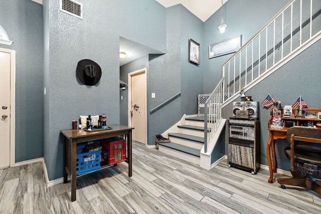3010 Adam Cv, Round Rock, TX 78681 - foyer entrance with wood finished floors, stairs, a high ceiling, and a textured wall