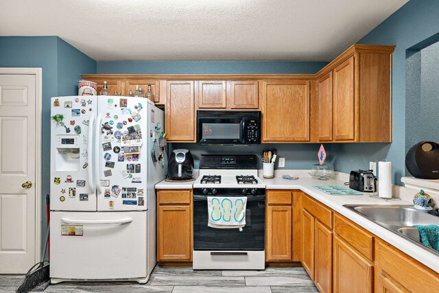 3010 Adam Cv, Round Rock, TX 78681 - kitchen with black appliances, light countertops, light wood finished floors, brown cabinets, and a textured ceiling