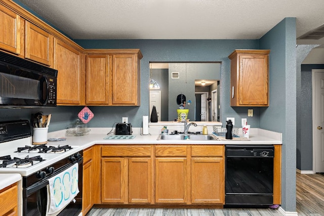 3010 Adam Cv, Round Rock, TX 78681 - kitchen featuring black appliances, light wood-style floors, light countertops, brown cabinets, and a textured ceiling