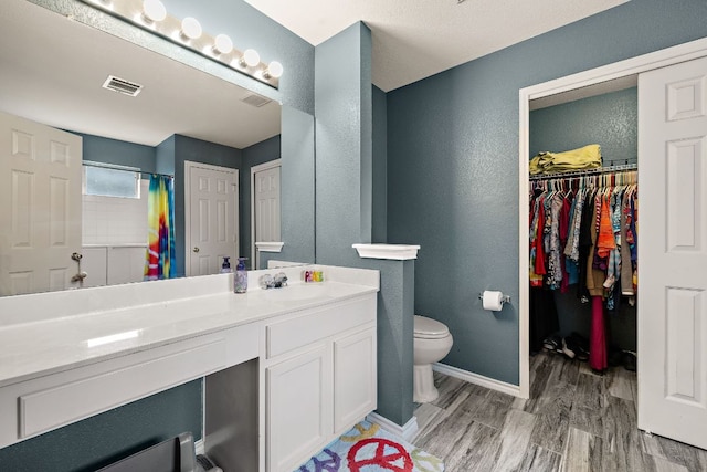 3010 Adam Cv, Round Rock, TX 78681 - bathroom featuring wood finished floors, vanity, a textured wall, a shower with curtain, and a walk in closet