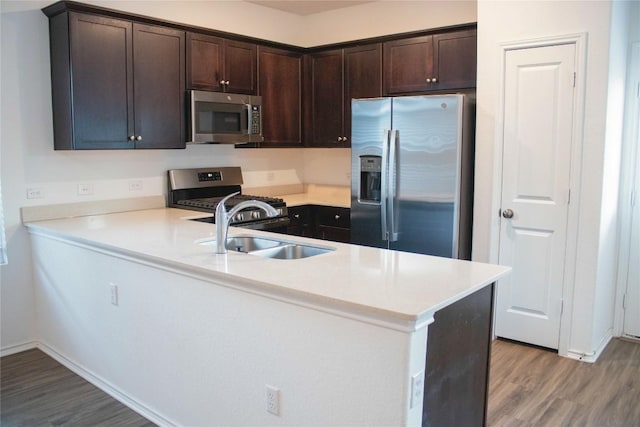 13801 Tordillo Dr, Elgin, TX 78621 - kitchen featuring stainless steel appliances, light wood-style flooring, dark brown cabinets, and a peninsula