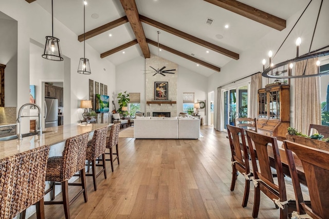 196 Westgate Loop, Horseshoe Bay, TX 78657 - dining area with high vaulted ceiling, light wood-style flooring, beam ceiling, a fireplace, and ceiling fan