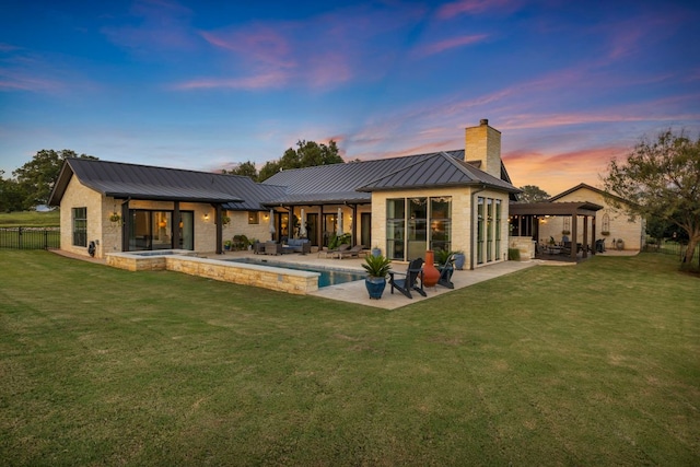 196 Westgate Loop, Horseshoe Bay, TX 78657 - rear view of property featuring a standing seam roof, a chimney, a patio, stone siding, and a metal roof