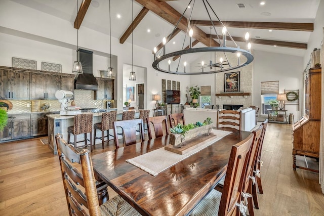 196 Westgate Loop, Horseshoe Bay, TX 78657 - dining room with beam ceiling, light wood-type flooring, a chandelier, high vaulted ceiling, and a fireplace