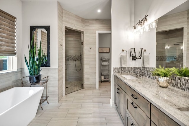 196 Westgate Loop, Horseshoe Bay, TX 78657 - bathroom featuring a shower stall, tile walls, vanity, a freestanding bath, and recessed lighting