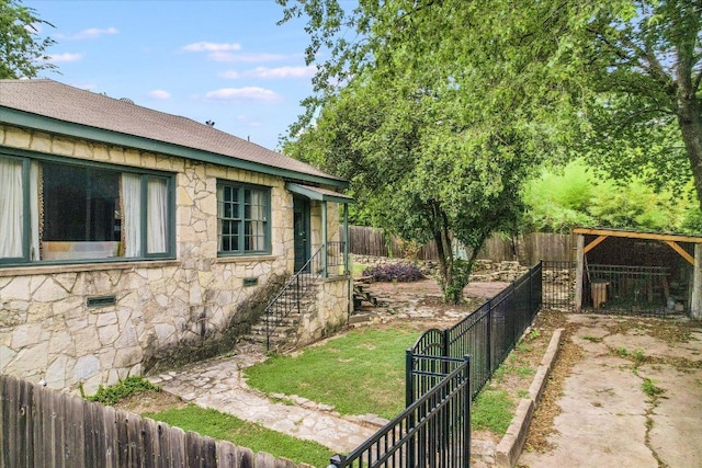 1410 Burford Pl, Austin, TX 78704 - view of property exterior featuring stone siding, a fenced backyard, and a shingled roof
