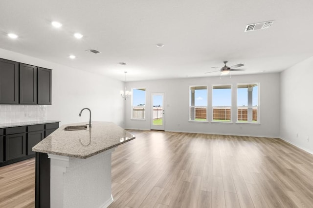 3715 Liberi Ln, Round Rock, TX 78665 - kitchen with an island with sink, light stone counters, a ceiling fan, recessed lighting, and light wood-style floors