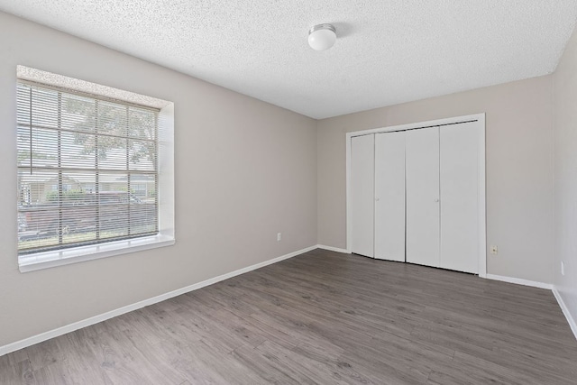 12323 Alderbrook Dr, Austin, TX 78758 - unfurnished bedroom featuring multiple windows, a textured ceiling, wood finished floors, and a closet