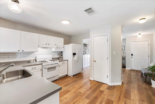 161 Buttercup Way, Kyle, TX 78640 - kitchen with white appliances, white cabinets, tasteful backsplash, light wood-type flooring, and under cabinet range hood