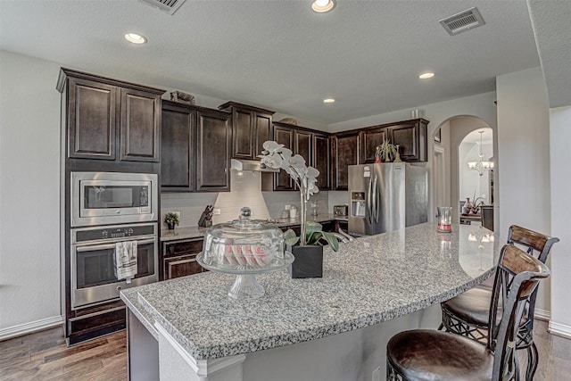 536 Middle Brook Dr, Leander, TX 78641 - kitchen with appliances with stainless steel finishes, arched walkways, backsplash, a large island, and a breakfast bar
