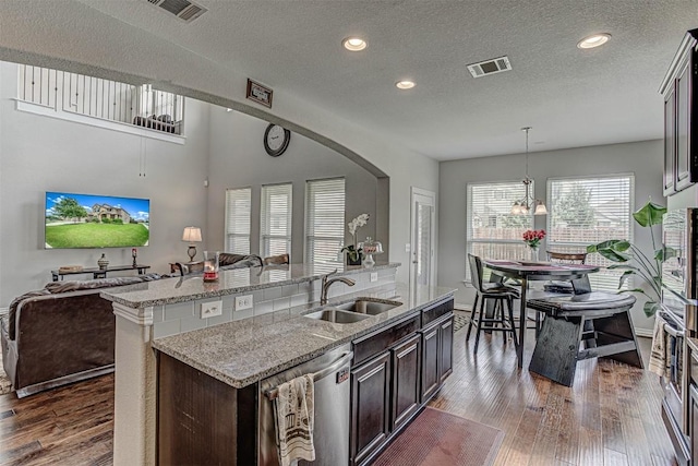 536 Middle Brook Dr, Leander, TX 78641 - kitchen featuring open floor plan, dishwasher, dark wood-type flooring, a textured ceiling, and a center island with sink