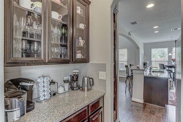 536 Middle Brook Dr, Leander, TX 78641 - bar area featuring arched walkways, decorative backsplash, dark wood-type flooring, recessed lighting, and a textured ceiling