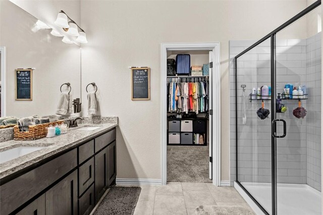 205 Goshen Dr, Dripping Springs, TX 78620 - full bathroom with double vanity, a stall shower, a walk in closet, and tile patterned floors