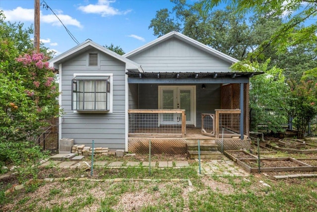 18000 Lafayette Park Rd, Jonestown, TX 78645 - view of front facade with french doors, a vegetable garden, and a wooden deck