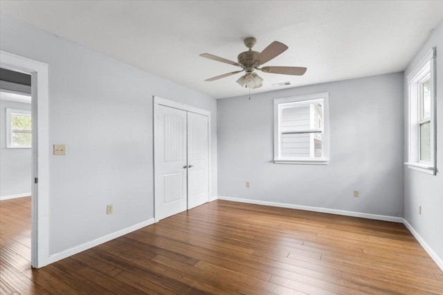 18000 Lafayette Park Rd, Jonestown, TX 78645 - unfurnished bedroom featuring multiple windows, hardwood / wood-style floors, a closet, and a ceiling fan