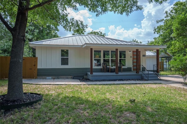5714 Ave D, Austin, TX 78752 - view of front facade with a front lawn, a metal roof, covered porch, and board and batten siding