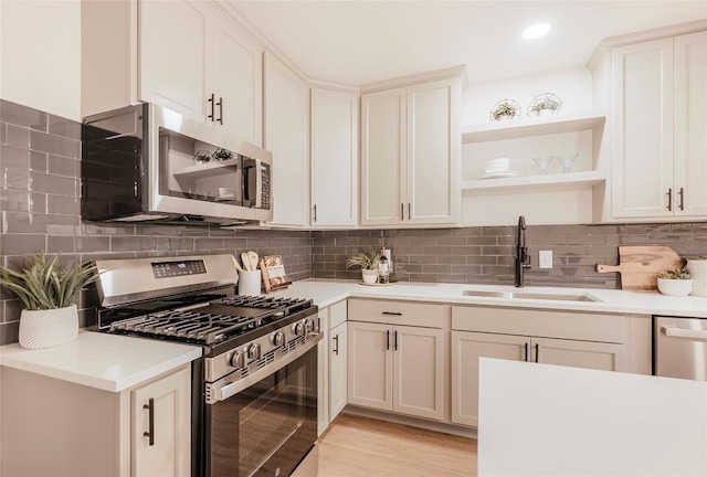 5714 Ave D, Austin, TX 78752 - kitchen featuring stainless steel appliances, open shelves, light countertops, backsplash, and light wood-type flooring