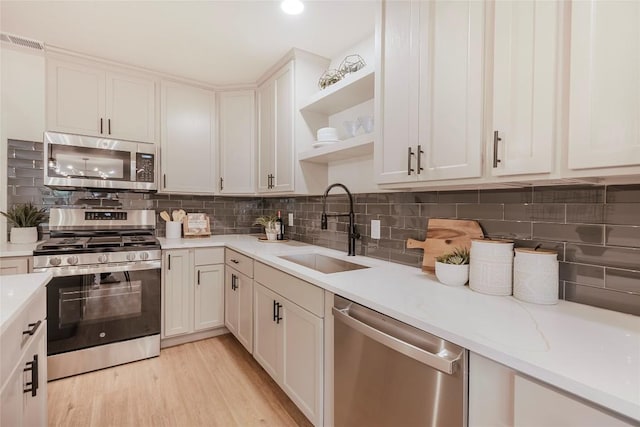5714 Ave D, Austin, TX 78752 - kitchen with appliances with stainless steel finishes, open shelves, tasteful backsplash, and white cabinetry