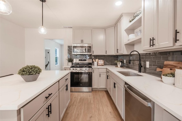 5714 Ave D, Austin, TX 78752 - kitchen with stainless steel appliances, open shelves, light wood finished floors, tasteful backsplash, and decorative light fixtures