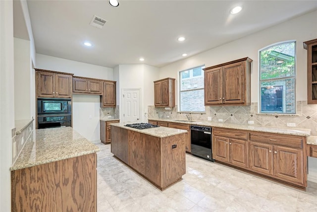 1160 Waimea Bnd, Round Rock, TX 78681 - kitchen with black appliances, a center island, light stone counters, backsplash, and recessed lighting