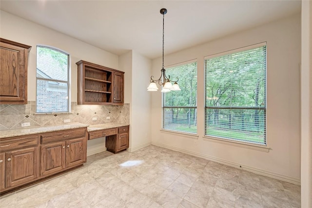 1160 Waimea Bnd, Round Rock, TX 78681 - kitchen with built in desk, open shelves, tasteful backsplash, decorative light fixtures, and light stone counters