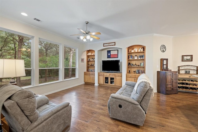 236 Pony Express Dr, Smithville, TX 78957 - living area with crown molding, a ceiling fan, dark wood-style flooring, built in shelves, and arched walkways