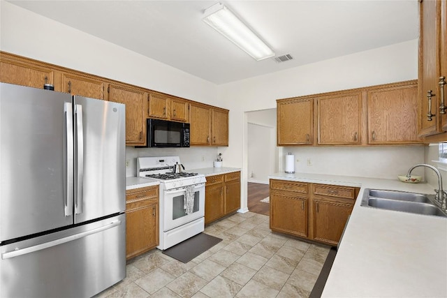 5910 Abilene Trl, Austin, TX 78749 - kitchen with freestanding refrigerator, gas range gas stove, black microwave, and brown cabinets
