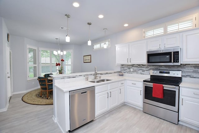 106 Bass St, Georgetown, TX 78633 - kitchen featuring stainless steel appliances, a chandelier, a peninsula, light wood-style flooring, and tasteful backsplash