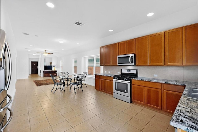 7619 Europa Ave, Round Rock, TX 78665 - kitchen with stainless steel appliances, light tile patterned flooring, brown cabinetry, tasteful backsplash, and recessed lighting
