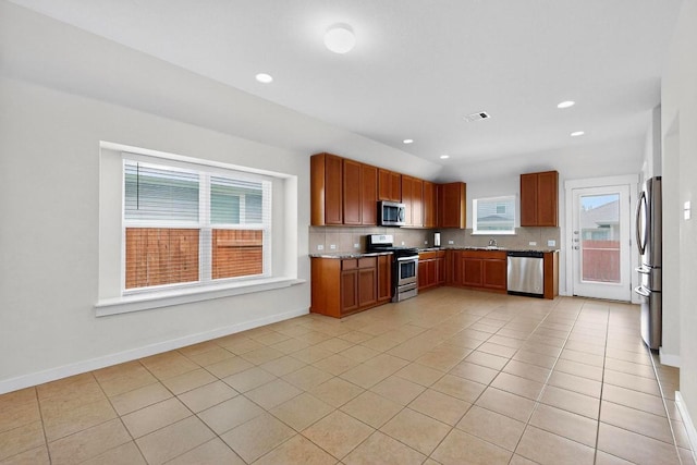 7619 Europa Ave, Round Rock, TX 78665 - kitchen featuring stainless steel appliances, decorative backsplash, light tile patterned flooring, light stone countertops, and brown cabinets