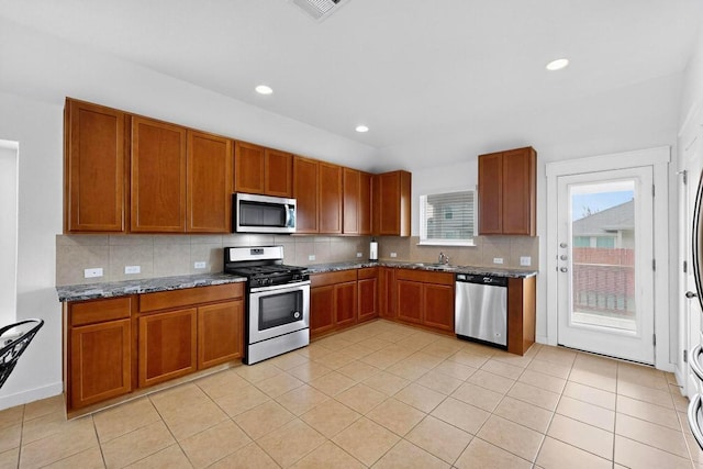 7619 Europa Ave, Round Rock, TX 78665 - kitchen featuring appliances with stainless steel finishes, brown cabinetry, decorative backsplash, and recessed lighting