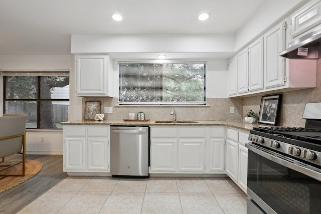12706 Shemya Cv, Austin, TX 78729 - kitchen featuring stainless steel appliances, under cabinet range hood, white cabinetry, light stone counters, and recessed lighting