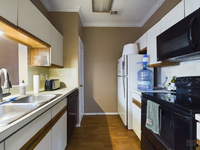 2804 Rio Grande St Unit 308, Austin, TX 78705 - kitchen with black appliances, dark wood finished floors, light countertops, white cabinetry, and ornamental molding