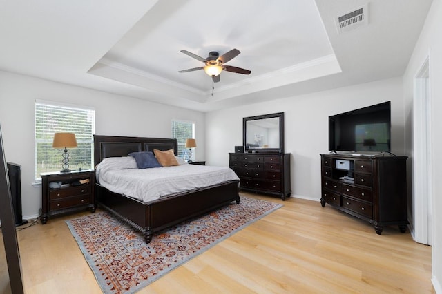 5601 Malcom Trl, Austin, TX 78754 - bedroom with a raised ceiling, light wood-style floors, multiple windows, ornamental molding, and a ceiling fan