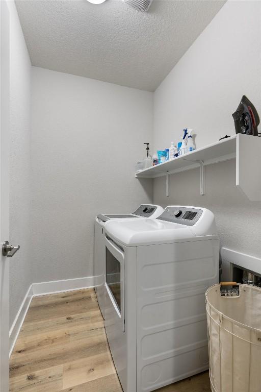 3101 Maysilee St, Austin, TX 78728 - washroom featuring washing machine and dryer, light wood-style floors, and a textured ceiling