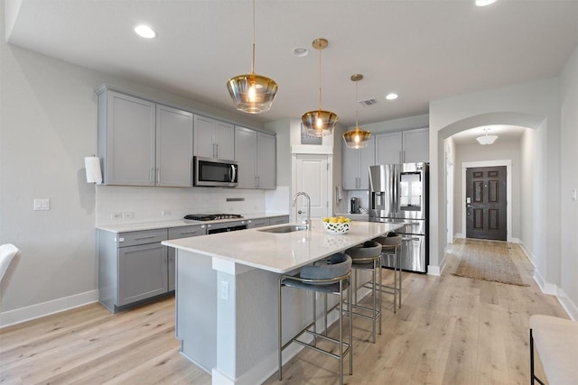 3101 Maysilee St, Austin, TX 78728 - kitchen featuring stainless steel appliances, gray cabinets, arched walkways, light wood-style flooring, and recessed lighting