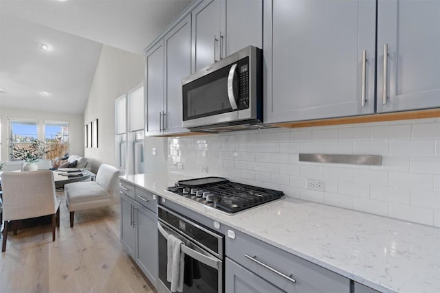 3101 Maysilee St, Austin, TX 78728 - kitchen featuring appliances with stainless steel finishes, gray cabinets, lofted ceiling, light wood finished floors, and recessed lighting